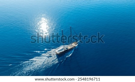  traditional gulet ship gracefully sailing on the calm sea, with its sails catching the gentle breeze and the turquoise waters shimmering under the sunlight.