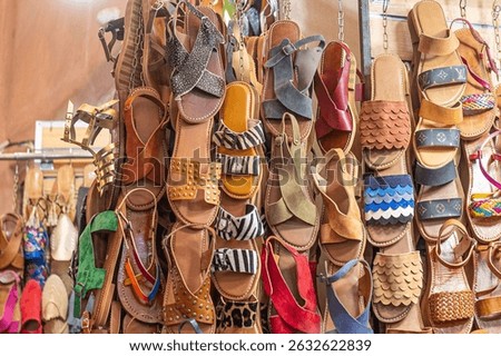 Traditional handmade leather sandals are displayed for sale in a bustling souk in marrakech, morocco