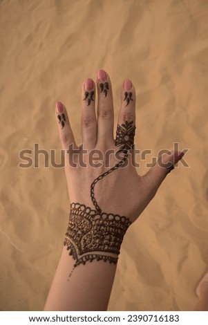 Traditional henna art tattoo on the hand of a woman  with dune background during desert safari in Dubai