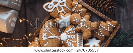 Traditional holiday homemade gingerbread cookies in a vintage wooden box. Craft paper with Christmas word. Festive mood, cozy home atmosphere, handmade toys, fir tree branches, fairy lights banner