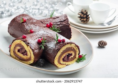 Traditional homemade Christmas cake. Yule log or Buche de Noel. Sponge cake with chocolate cream, ganache, decorated with cranberries. 