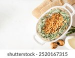 Traditional homemade green bean casserole. Top down view table scene on a white marble background with copy space. Holiday food concept.