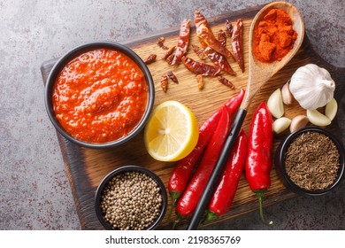 Traditional homemade harissa hot chili pepper sauce paste with garlic and olive oil on the bowl on wooden board with ingredients closeup. Horizontal top view from above
 - Powered by Shutterstock