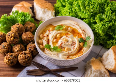 Traditional homemade hummus, falafel and chickpea served with salad and pita and spices on wooden table. Jewish Cuisine. Top view