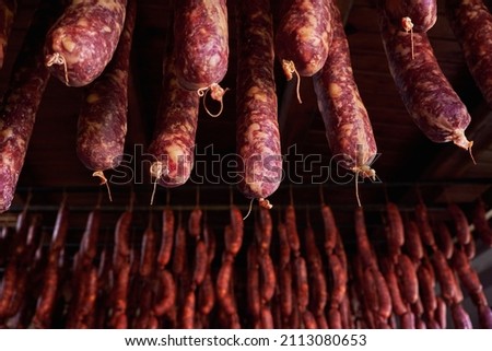 Traditional homemade saucissons and spanish chorizos hanging to dry in the curing room 
