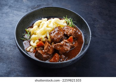 Traditional Hungarian braised venison goulash with vegetable and spaetzle in spicy sauce served as close-up in a Nordic design bowl 