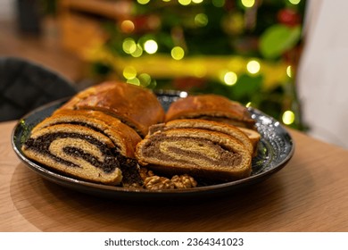 traditional hungarian christmas cookie calles bejgli filled with walnut and poppy seed with christmas tree background .