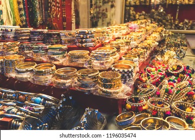 Traditional Indian Bangles And Bracelets At The Street Market In Udaipur, Rajasthan, India. Jewelry Made Of Gold-plated Metal With Multicolored Stones In The Asian Style. Tibetan Bracelets