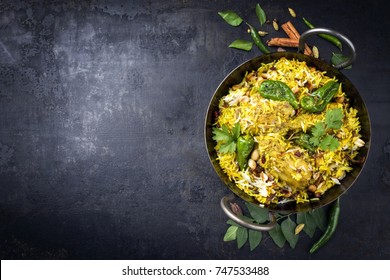 Traditional Indian chicken biryani with nuts and raisins as close-up in a korai with copy space left