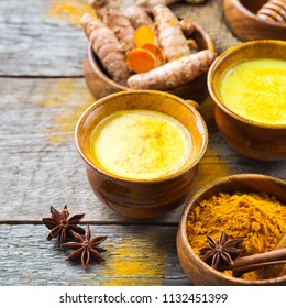 Traditional indian drink turmeric golden milk with ingredients, ginger, curcuma, honey on a rustic wooden table