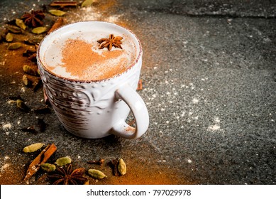 Traditional indian masala chai tea with spices - cinnamon, cardamom, anise, dark stone background. Copy space