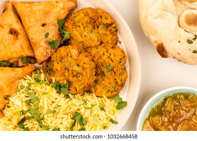 Traditional Indian Onion Bhaji And Samosas With Yellow Pilau Rice, Against A Grey Background With Mango Chutney And Flat Bread, Close Up Top View With No People