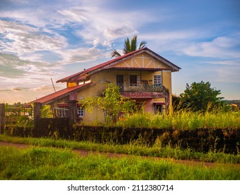 Traditional Indian village house surrounded by green grass and beatiful sunset sky. Village landscape.