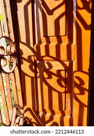 Traditional Indian Wooden Window With Iron Bars, Of The House Of Middle Class Family. They Are Using Old Unused Clothes As The Window Curtains Giving An Idea Of The Colorful Culture.Window Pane Shadow