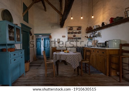 Traditional interior of old village kitchen in historic country house with stucco walls, wooden beams, oak wood furniture, vintage kitchenware