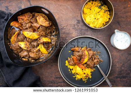 Traditional Iranian khoresh beh stew with chunks of lamb, quinces and saffron rice as top view in a modern design cast-iron roasting dish 