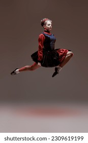 Traditional Irish dances. Beautiful professional dancer woman in national Irish costume makes a high jump during the dance. Studio full-length portrait. - Shutterstock ID 2309619199