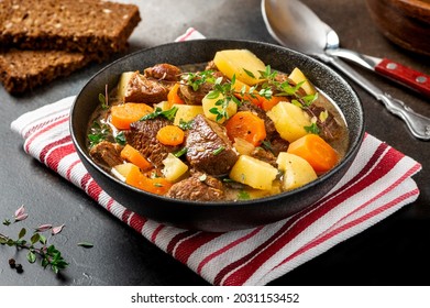Traditional Irish stew in a black bowl on a dark background. Stew of lamb, potatoes, onions, carrots, and thyme. Traditional dish of St. Patrick's Day. - Shutterstock ID 2031153452