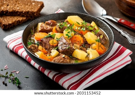 Traditional Irish stew in a black bowl on a dark background. Stew of lamb, potatoes, onions, carrots, and thyme. Traditional dish of St. Patrick's Day.