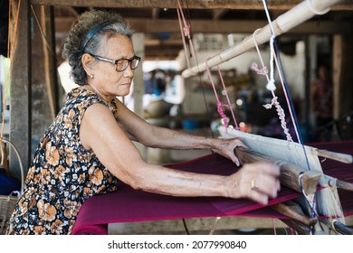 Traditional Isan Thai silk weaving. old woman hand weaving silk in traditional way at manual loom. Kalasin, Thailand.