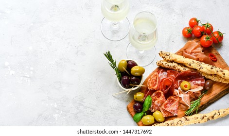 Traditional Italian appetizers ( antipasto ) : salami, bresaola, prosciutto, olives. Aperitif in Italy in Florence, Rome, aperitif in Milan. Two glasses of Prosecco and sticks of cereal bread