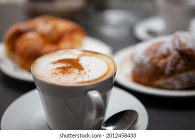 Traditional Italian breakfast. Fresh croissants with cream and sugar powder, espresso coffee and cappuccino on a black wooden table in Milan, Lombardy, Italy. European food and pastry. - Powered by Shutterstock