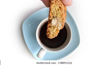 Traditional Italian Cantuccino (or Cantuccio) Almond Biscuit (cookie) Ready To Be Dunked In An Espresso Coffee Cup On A Light Blue Coaster, Isolated On White Background