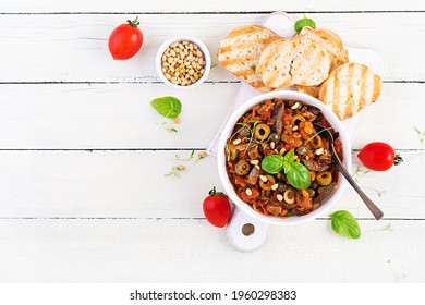 Traditional Italian Caponata and toast on a wooden white table. Sicilian caponata. Top view, above, flat lay