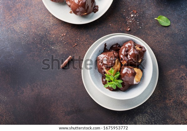 Traditional italian dessert\
profiteroles with chocolate cream, top view and selective focus\
image