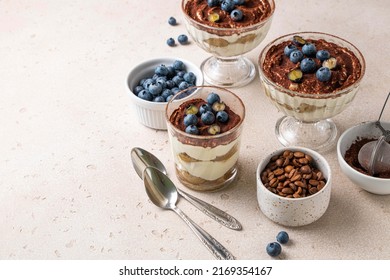 Traditional Italian dessert tiramisu with blueberries in glass. Individual trifle. Homemade layered cake with berries in cup. Copy space. Selective focus.