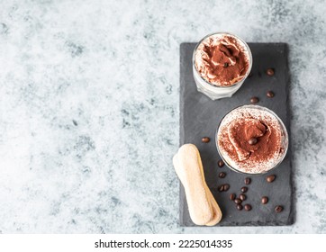 Traditional Italian dessert tiramisu, stone background. Coffee flavored portion dessert made of savoiardi and mascarpone decorated with cocoa powder.