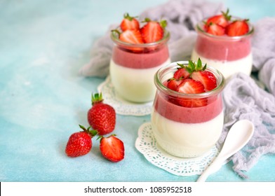 Traditional italian dessert vanilla strawberry panna cotta in a vintage jars with fresh berries on a turquoise slate,stone or concrete background.Copy space.