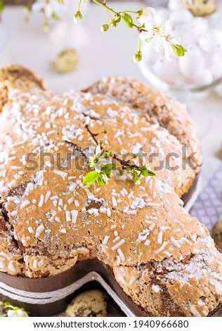 Traditional Italian desserts for Easter - Easter dove. Festive pastries with almonds and sugar icing on a light background and flowering branches, Easter decor and eggs. vertical. close-up
