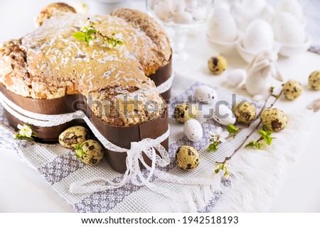 Traditional Italian desserts for Easter - Easter dove. Festive pastries with almonds and sugar icing on a light background and flowering branches, Easter decor and eggs. close-up