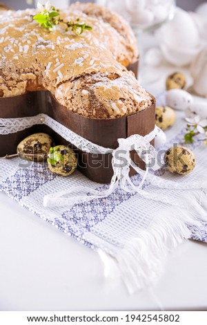 Traditional Italian desserts for Easter - Easter dove. Festive pastries with almonds and sugar icing on a light background and flowering branches, Easter decor and eggs. vertical. close-up