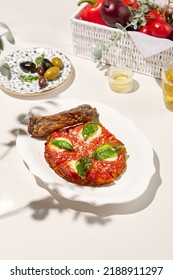 Traditional Italian Dish - Milanese Steak In Breaded And Parmesan On White Ceramic Plate. Milanese Beef With Tomato Sauce And Basil. Italian Beef Steak Alla Schnitzel With Bone. Italian Chop Beef