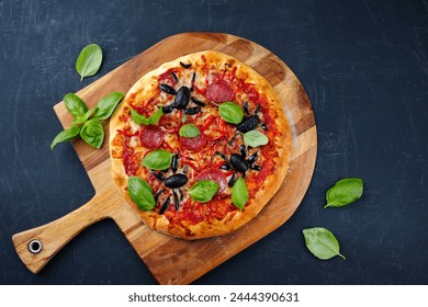 Traditional Italian Halloween spider pizza with salami, chili and olives designed as spiders served as a top view on a rustic wooden pizza shovel, board - Powered by Shutterstock