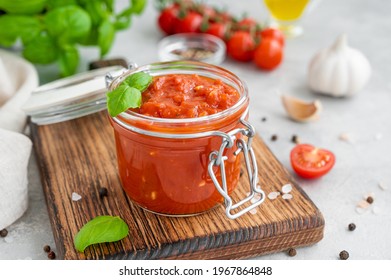 Traditional Italian Marinara Sauce In A Jar On A Concrete Background With Spices And Ingredients. Copy Space