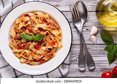 Traditional italian pasta bolognese on a white plate on a wooden background, top view.
