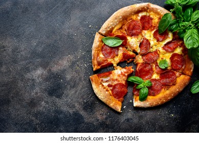 Traditional italian pizza pepperoni with salami and cheese on a dark slate, stone, metal or concrete background.Top view with copy space. - Powered by Shutterstock