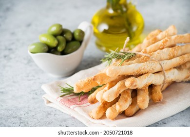 Traditional Italian snack grissini-breadsticks with olive oil and sesame seeds on a light background, selective focus