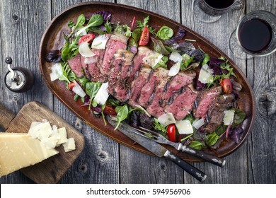 Traditional Italian Tagliata Steak With Parmesan And Salad As Close-up On A Plate