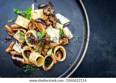 Traditional Italien calamarata noodles with mushroom and parmesan as top view on a plate with copy space right