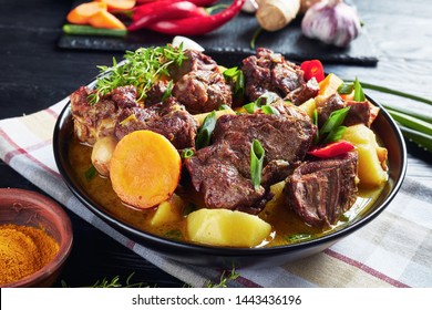 Traditional Jamaican Curry Goat – Slow Cooked Jamaican Goat Meat And Vegetables Spicy Curry In A Black Bowl On A Rustic Wooden Table, Close-up