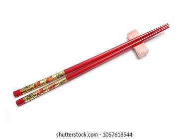 Traditional japanese bamboo with painted golden flowers on red chopsticks (hashi) lays on clow chopsticks  rest (hashi-oki) isolated on white background.