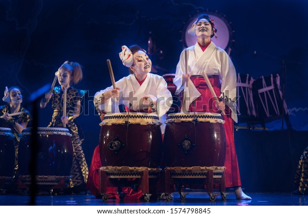 Traditional\
Japanese performance. Group of actresses in traditional kimono and\
fox masks drum taiko drums on the\
stage.