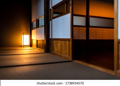 Traditional japanese room low angle view in house or ryokan with open shoji sliding paper doors tatami mat floor and lamp illuminated at night with nobody