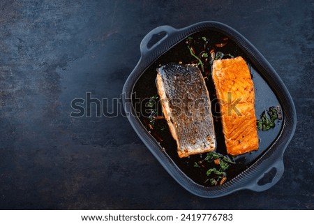 Traditional Japanese salmon fish teriyaki filet with soy souce and spinach as top view in a Nordic design pan with copy space left