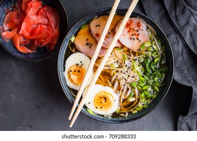 Traditional Japanese soup ramen with meat broth, asian noodles, seaweed, sliced pork, eggs and ginger on dark concrete background. Close up. Asian style food. Top view. Hot tasty ramen soup for dinner - Powered by Shutterstock