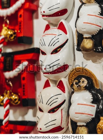 Traditional Japanese tourist souvenirs and gifts from Kyoto, Kansai, Japan, with daruma figures, kitsune fox, tengu mask, fridge magnets, toys figurines, key ring keychain, in a local vendor gift shop